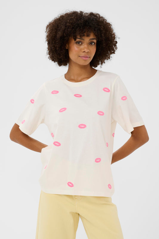 Woman wearing a white t-shirt with pink lip prints on a plain background