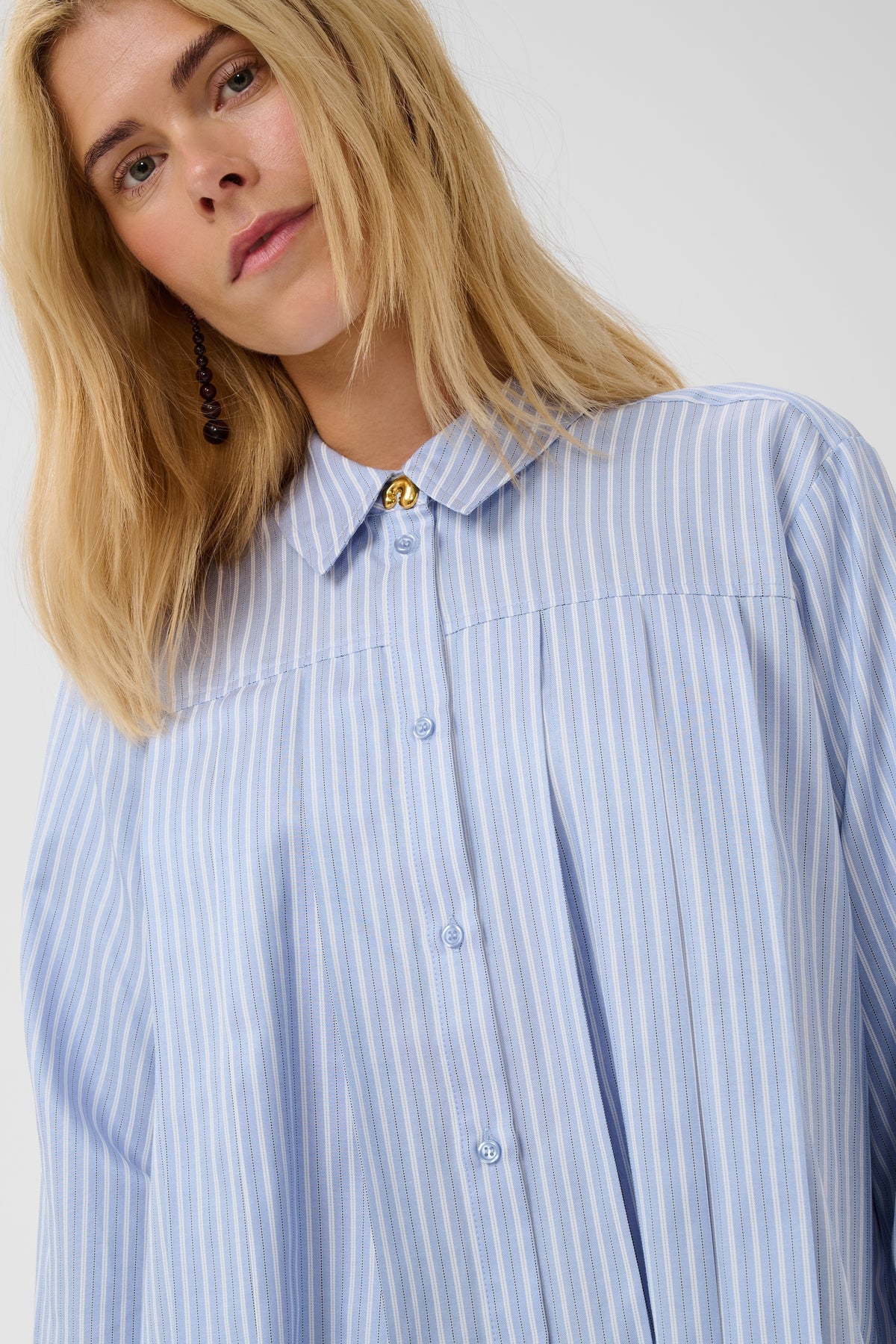 Woman wearing a blue and white striped shirt against a plain background