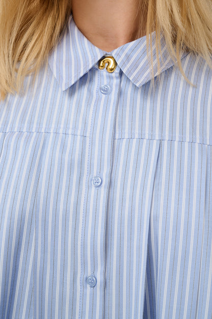 Close-up of a blue and white striped shirt with a gold button.