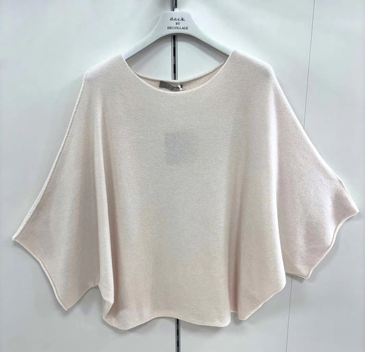 Beige poncho-style top on a hanger against a white background