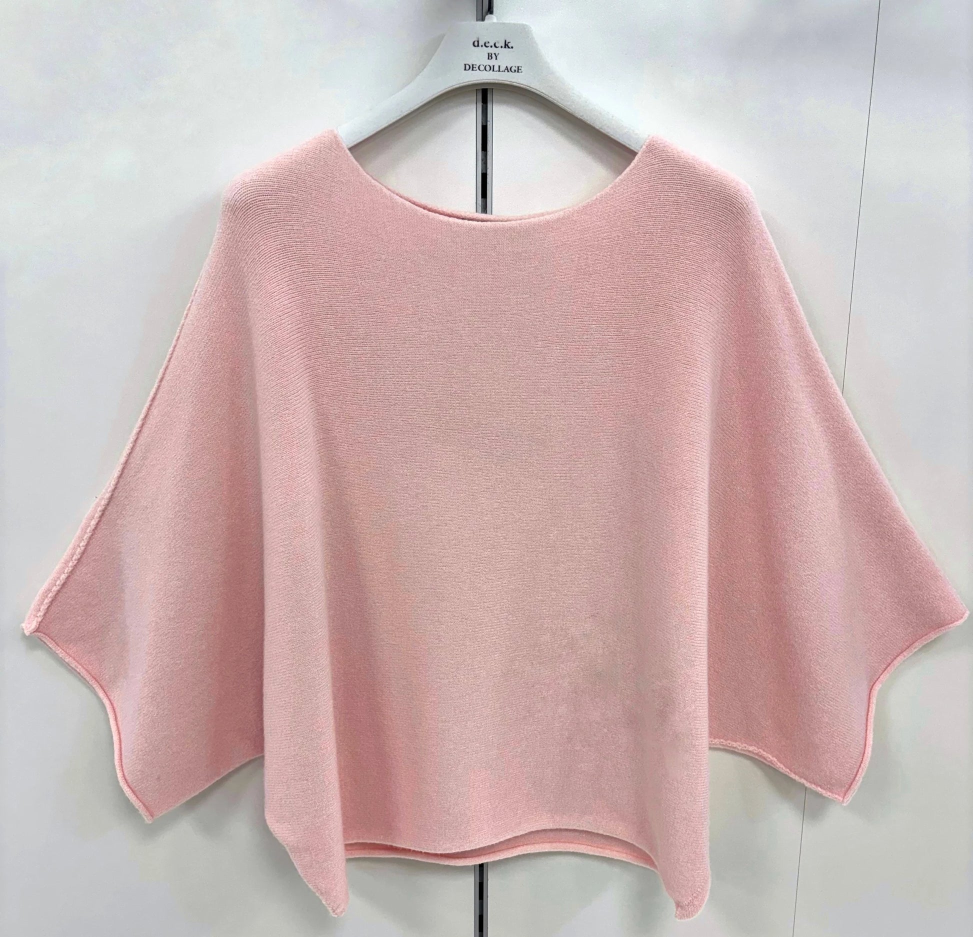 Pink poncho on a hanger against a white background