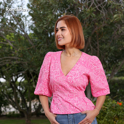 Woman wearing a pink patterned top with trees in the background