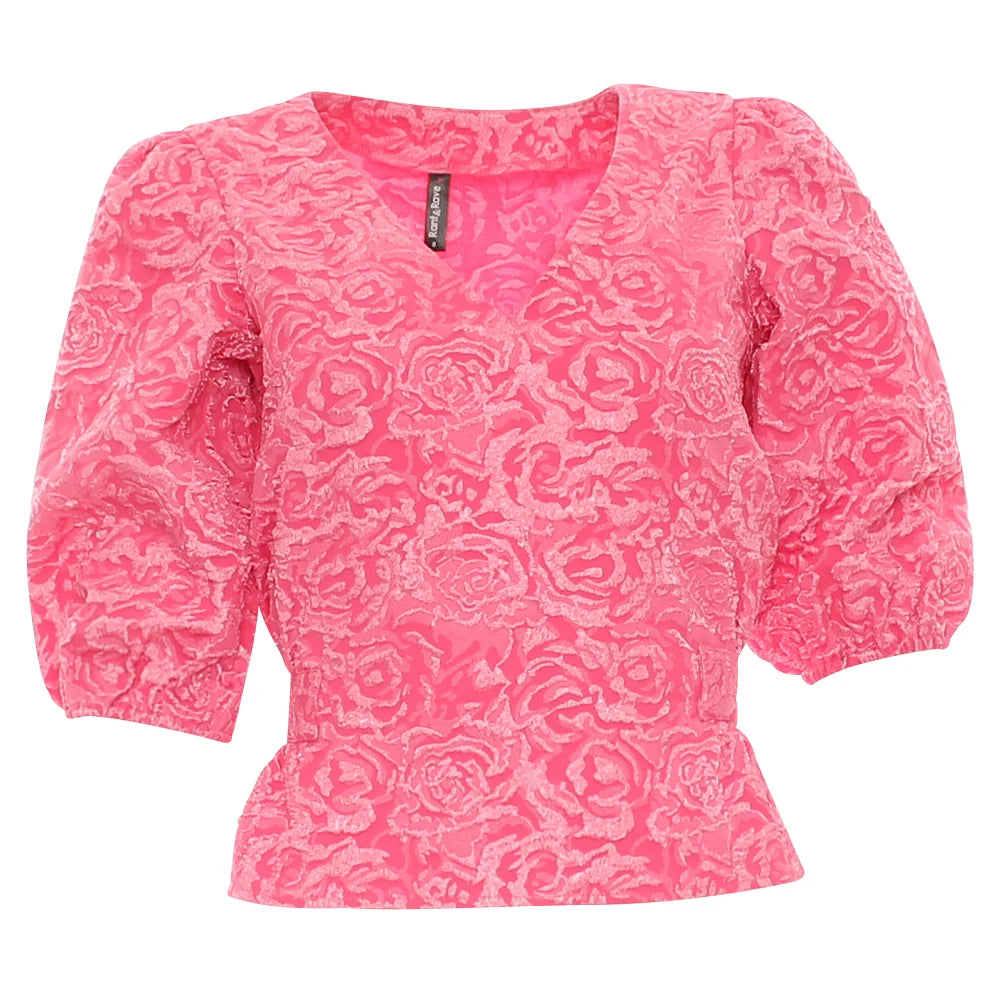 A bright pink short-sleeve blouse with a textured rose pattern, featuring a V-neckline and puffed sleeves, shown against a plain white background.