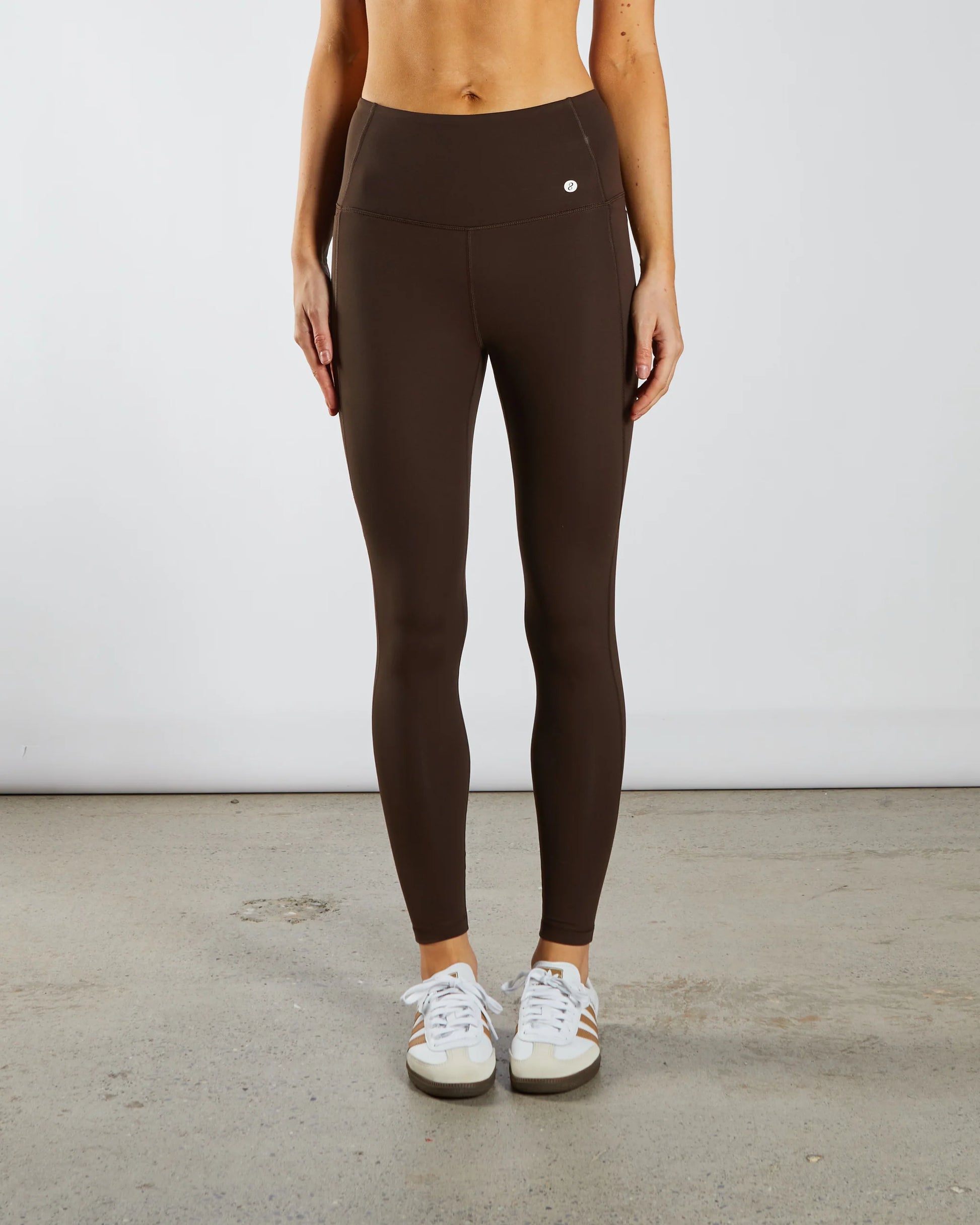 Person wearing brown leggings with a plain background