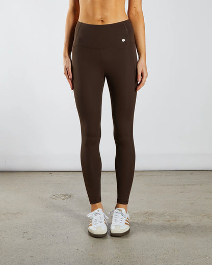 Person wearing brown leggings with a plain background