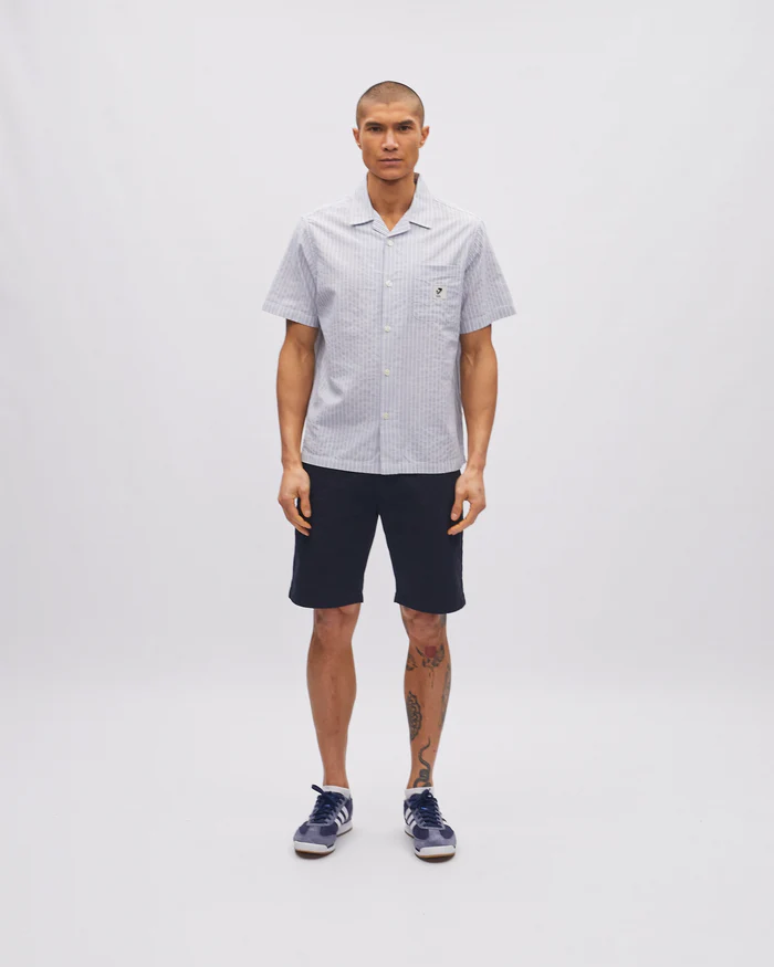 Man wearing a checkered shirt and dark shorts on a white background