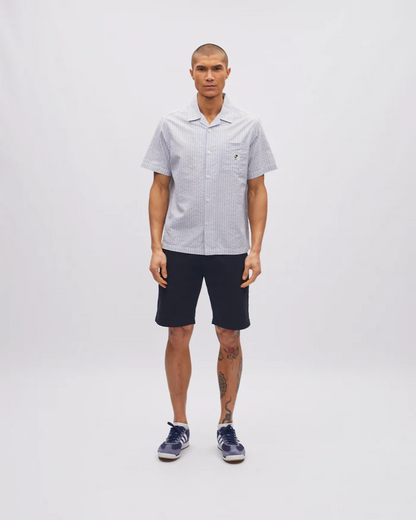 Man wearing a checkered shirt and dark shorts on a white background