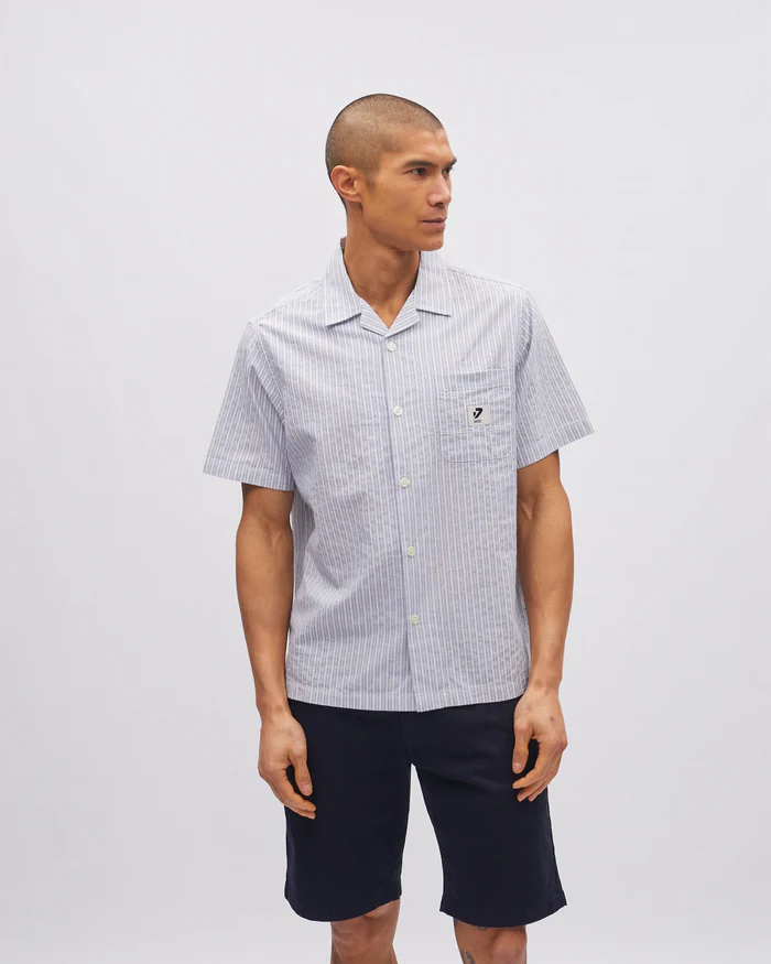 Man wearing a checkered shirt and dark shorts on a plain background