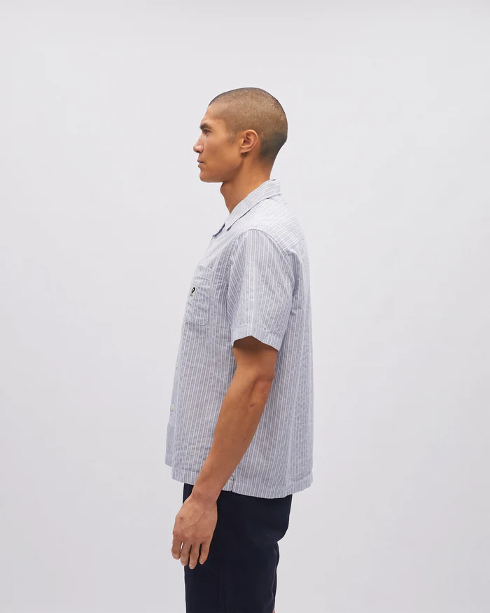 Man wearing a checkered shirt standing against a plain background