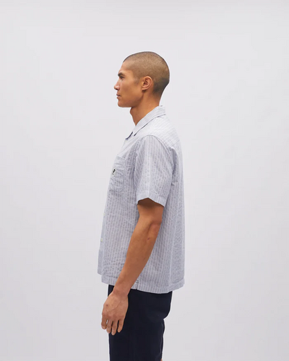 Man wearing a checkered shirt standing against a plain background