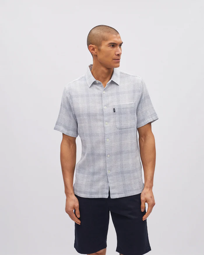 Man wearing a checkered shirt and shorts on a plain background