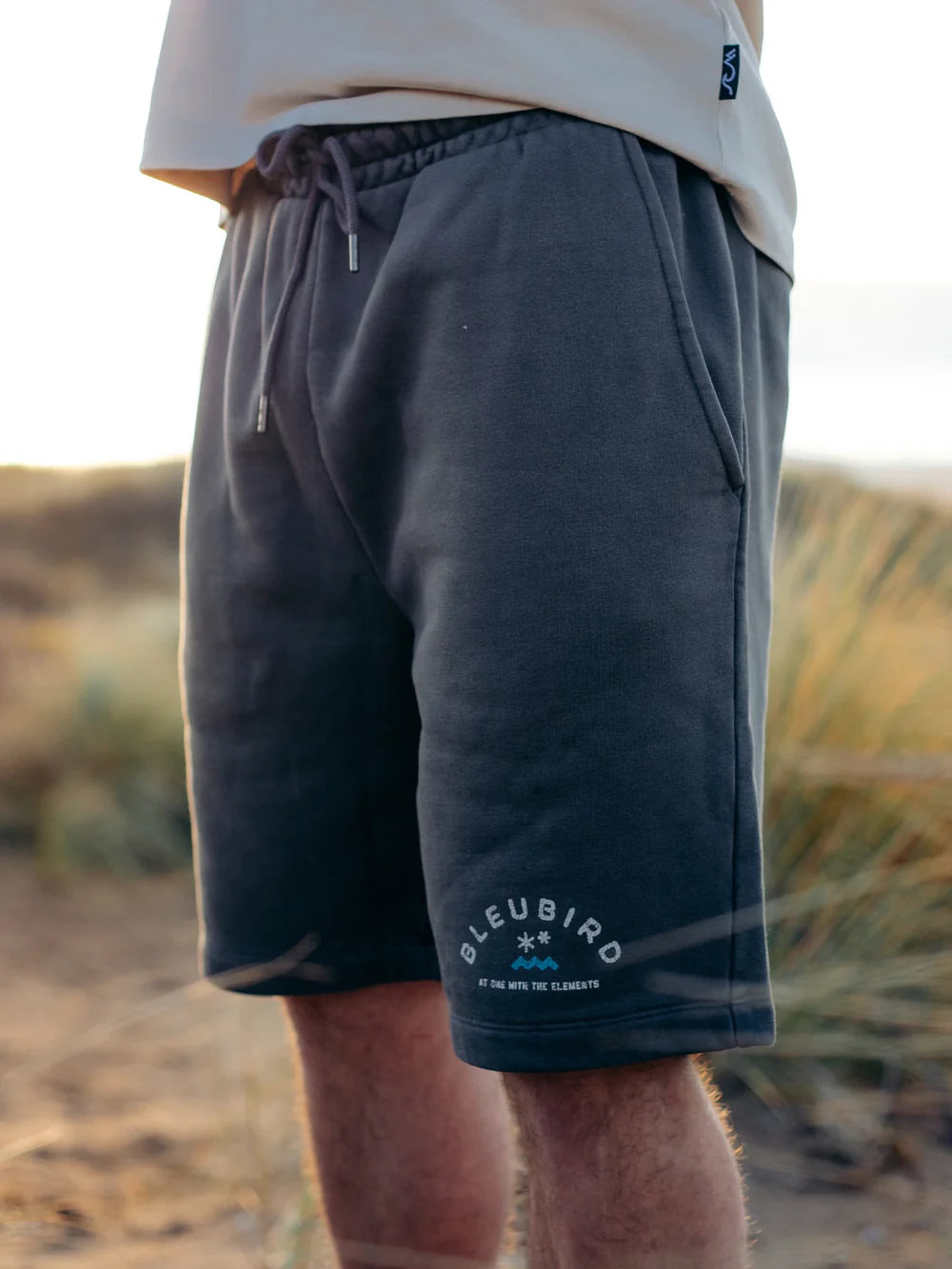 Person wearing dark shorts with a brand logo in a desert setting