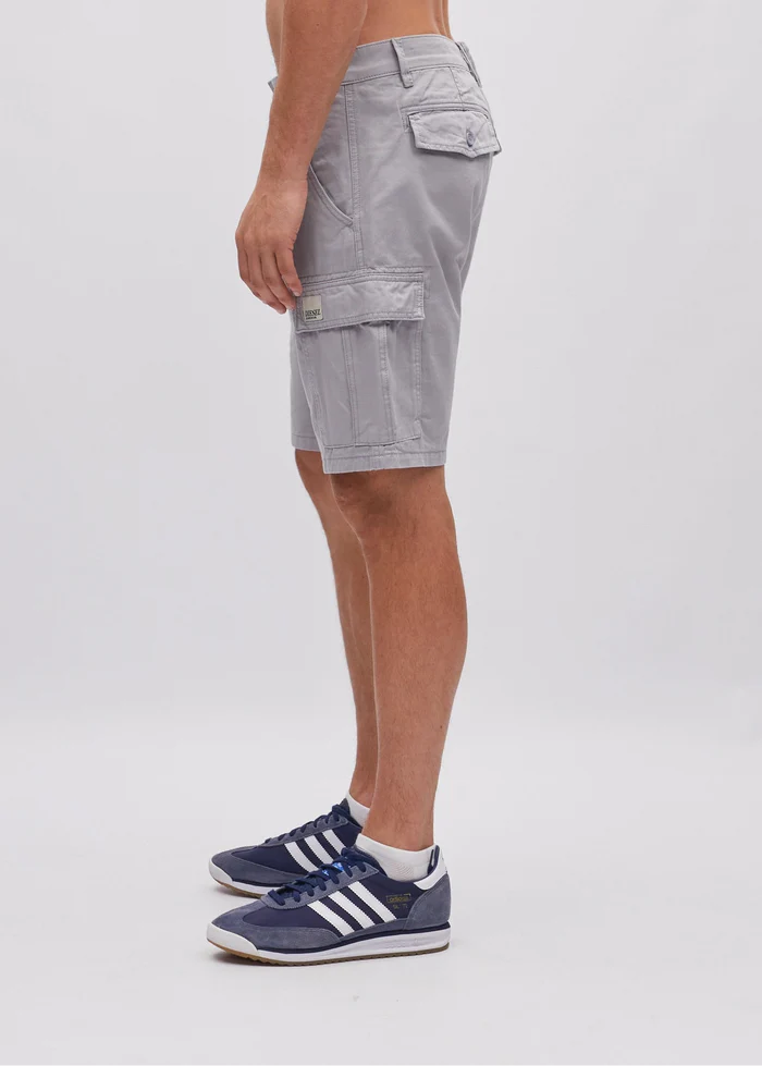Person wearing gray cargo shorts and Adidas sneakers on a white background