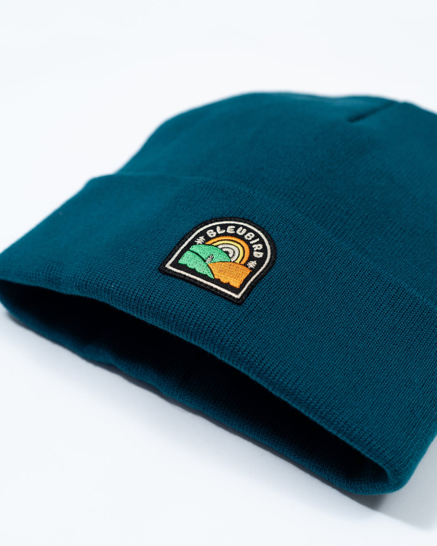 Teal beanie with a logo patch on a white background