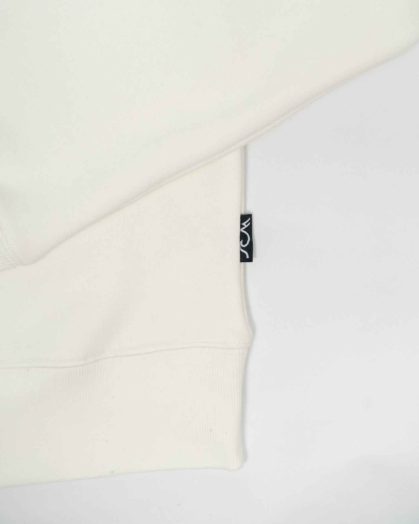 Close-up of a white garment with a brand tag on a light gray background