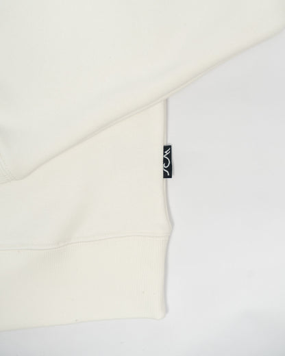 Close-up of a white garment with a brand tag on a light gray background