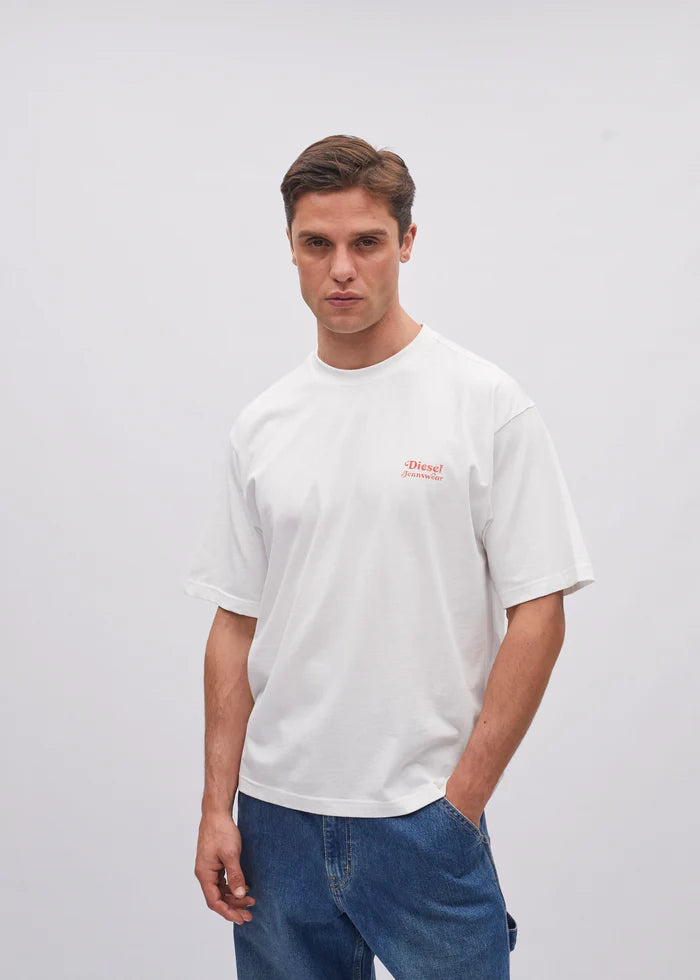 Man wearing a white t-shirt with a small red logo on a plain background