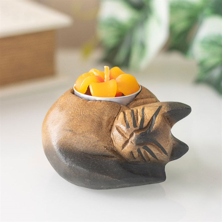 Wooden cat-shaped candle holder with a small bowl of candles on a white surface.