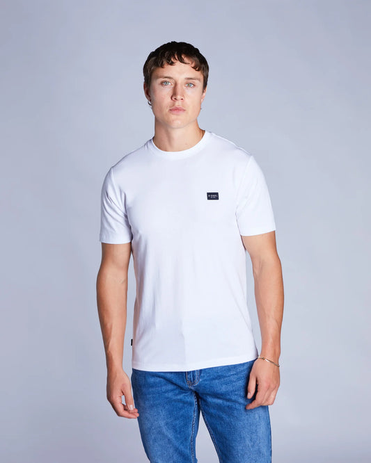 Man wearing a white t-shirt with a small logo on a plain background