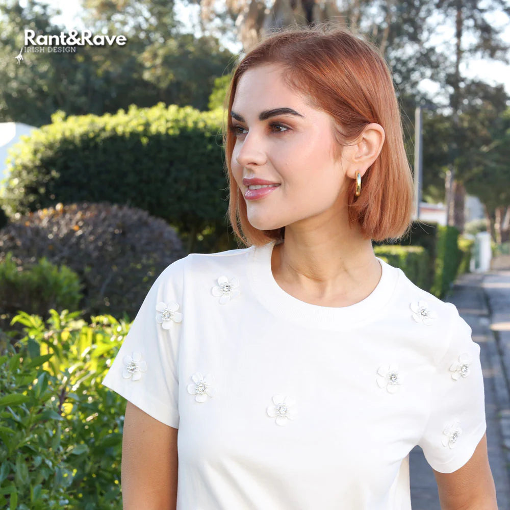 Woman with short hair wearing a white top outdoors