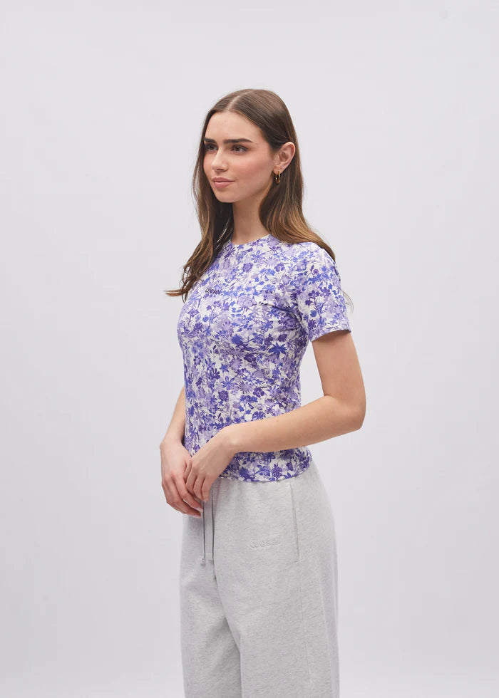 Woman wearing a purple floral top and gray pants on a white background