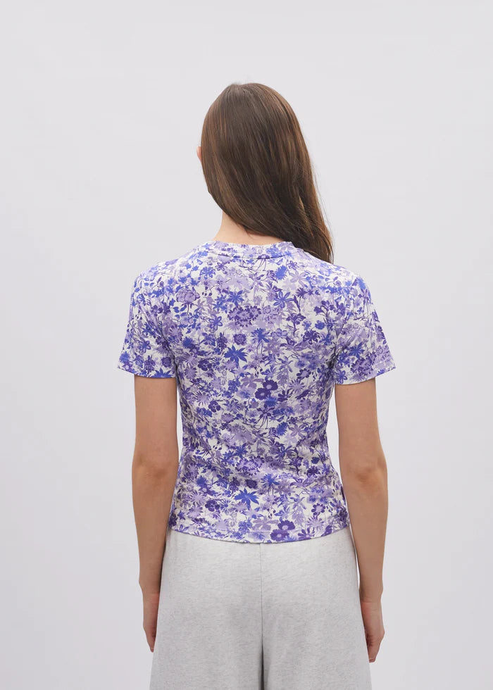 Woman wearing a blue floral patterned shirt on a plain background