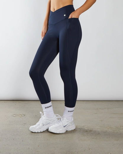 Person wearing navy leggings and white sneakers with a white background