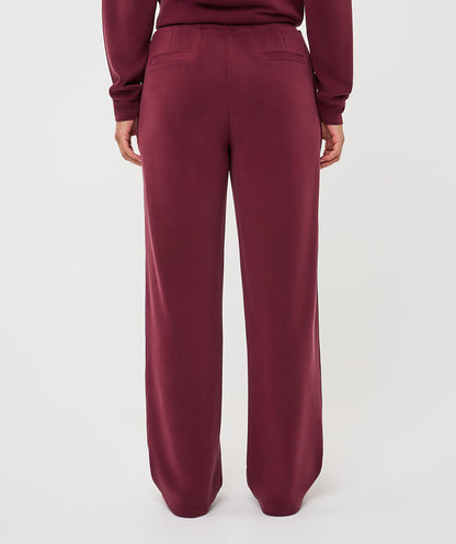 A person shown from the back wearing burgundy wide-leg sweatpants and a matching long-sleeve top against a plain light gray studio background.
