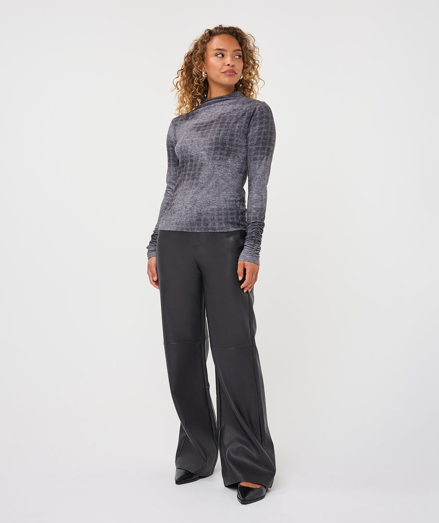 A woman modeling a gray textured long-sleeve mock neck top and black wide-leg trousers against a plain white studio background.