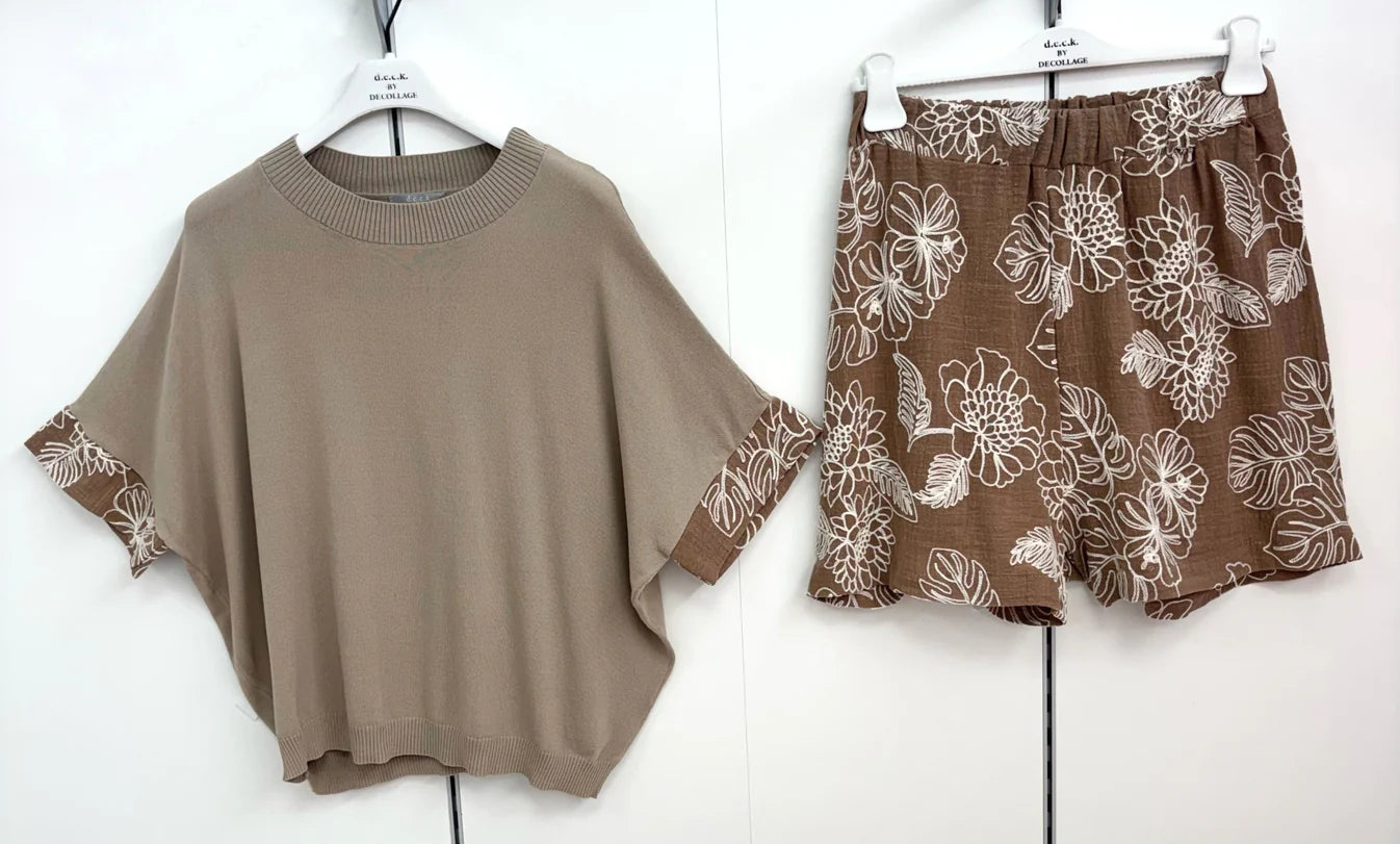 Brown sweater and floral shorts on hangers against a white background