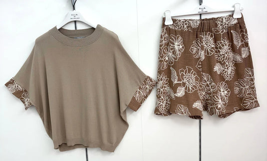 Brown sweater and floral shorts on hangers against a white background