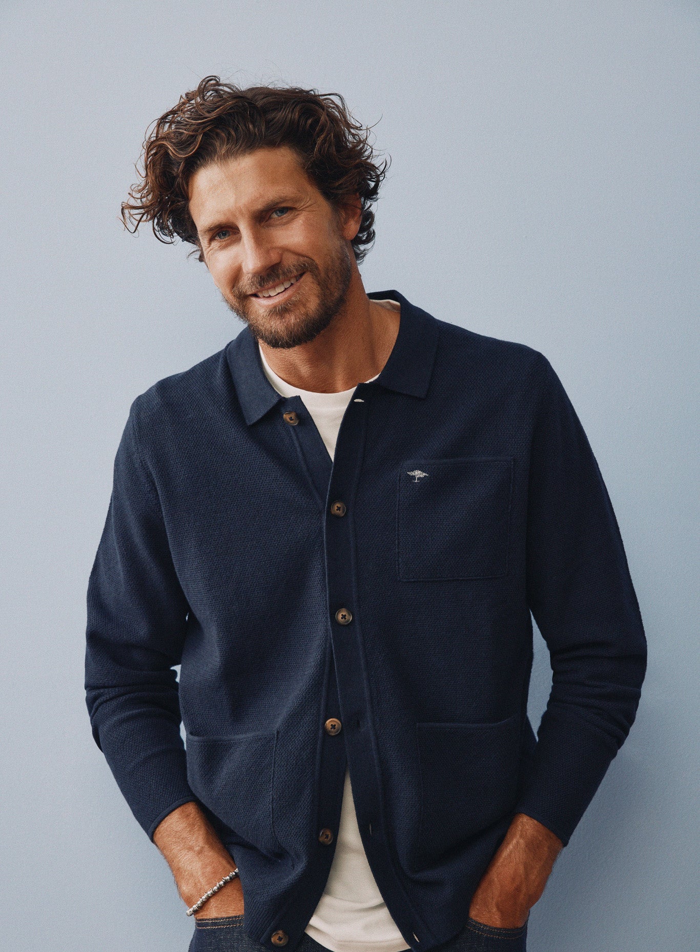 Man wearing a navy blue jacket with a logo on a gray background