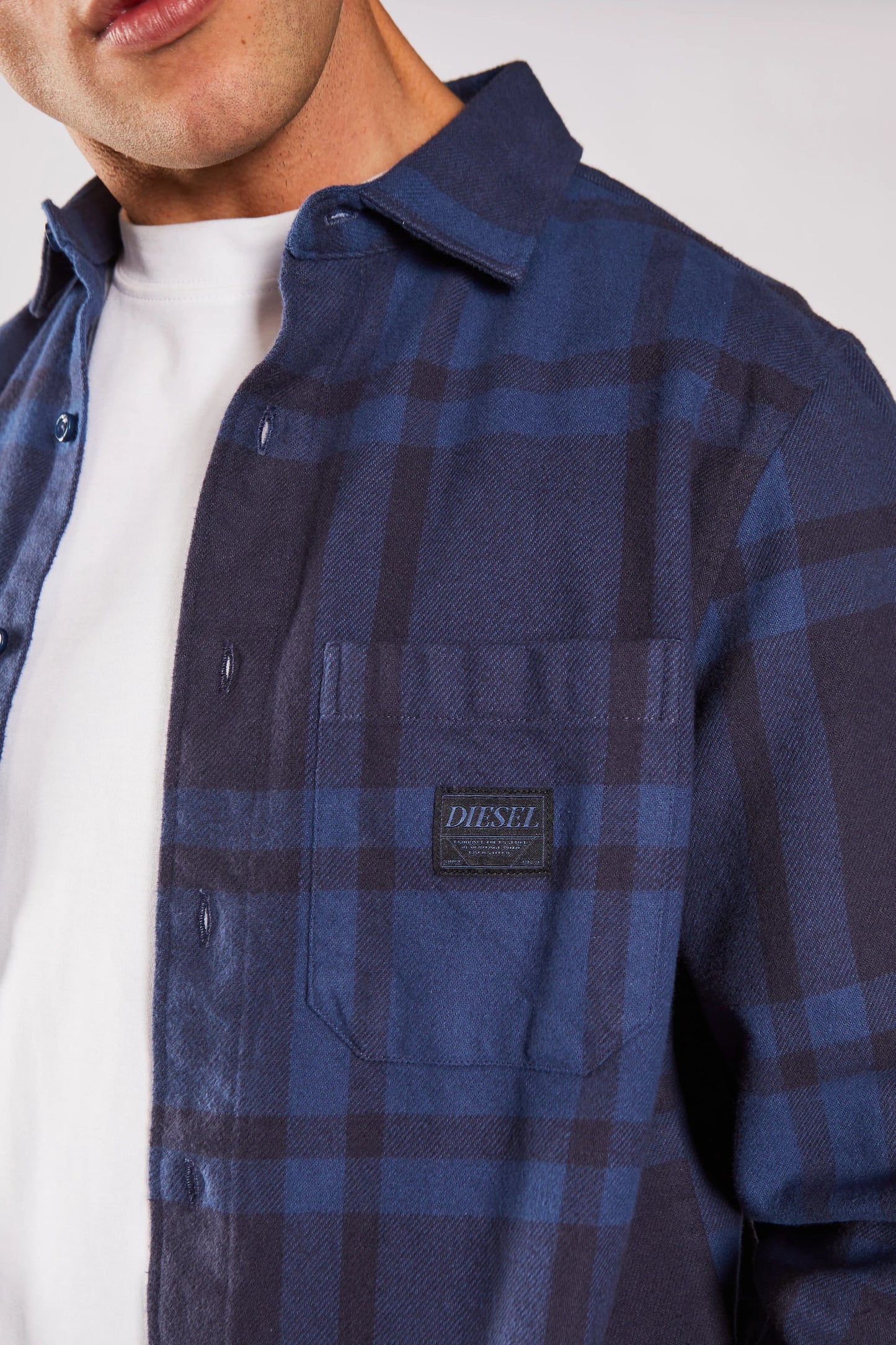 Blue plaid shirt with a Diesel logo patch on a white background