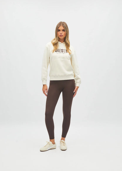 Women modelling against plain background cream hoodie with logo and brown leggings
