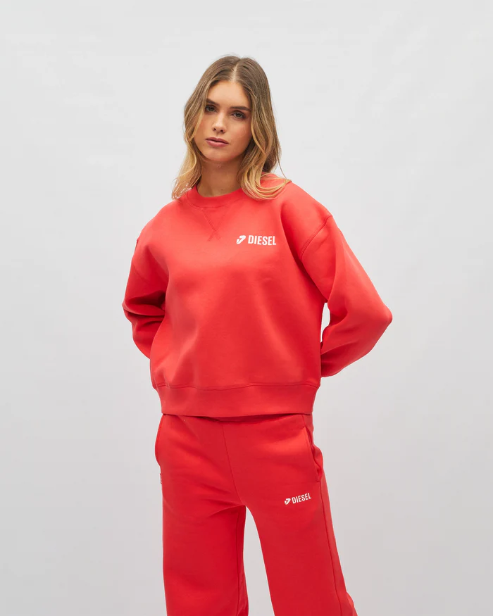 Person wearing a red Diesel sweatshirt and pants on a light gray background