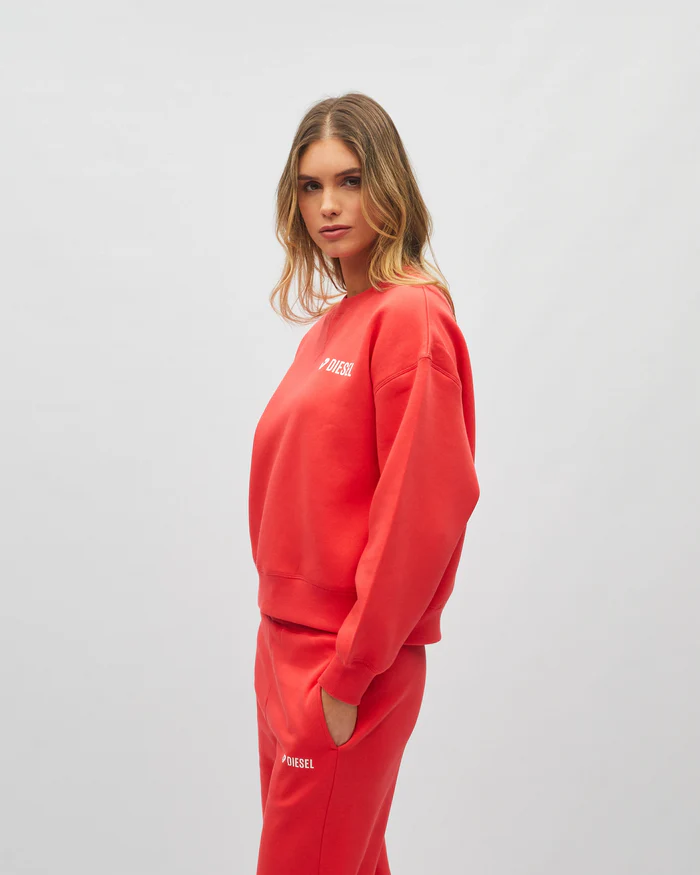 Person wearing a red 'Diesel' tracksuit on a white background