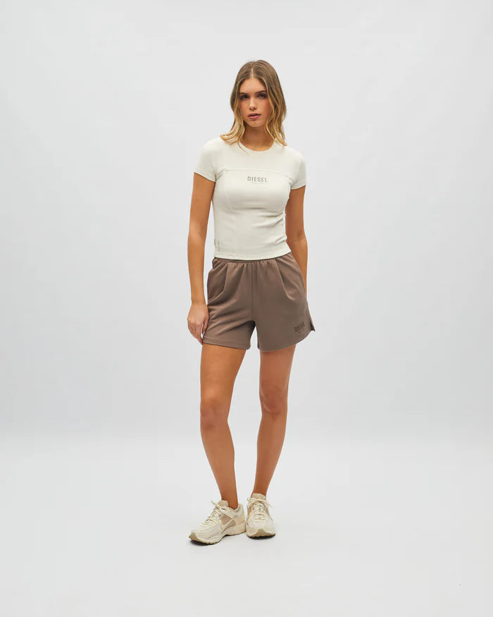 Woman wearing a white t-shirt and brown shorts on a plain background