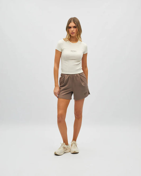 Woman wearing a white t-shirt and brown shorts on a plain background