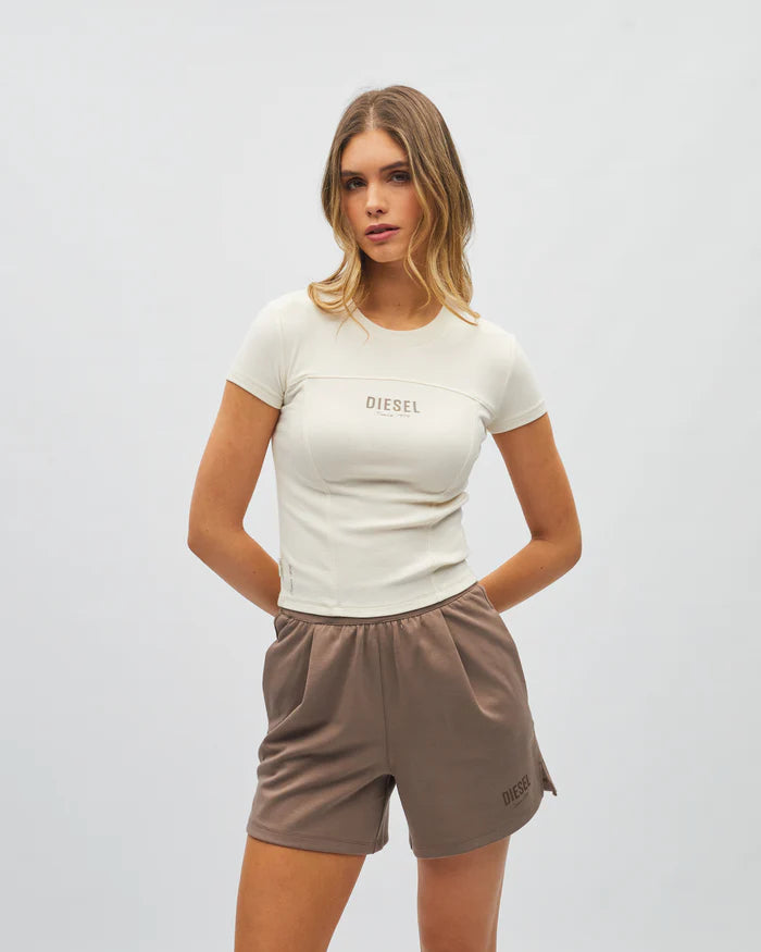 Woman wearing a white t-shirt and brown shorts on a plain background