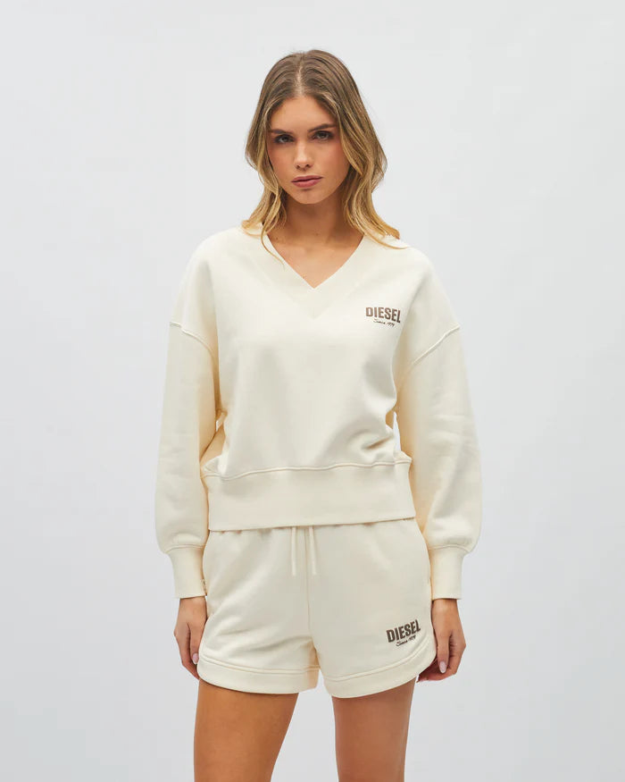 Woman wearing a cream-colored 'Diesel' sweatshirt and shorts on a white background