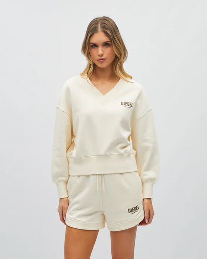 Woman wearing a cream-colored 'Diesel' sweatshirt and shorts on a white background