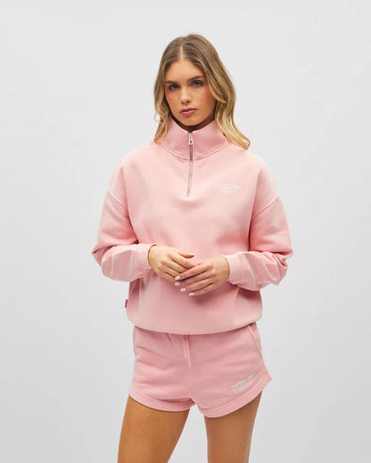 Woman wearing a pink tracksuit with a brand logo on a white background