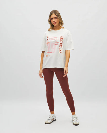 Woman wearing a white t-shirt with red text and maroon leggings on a white background