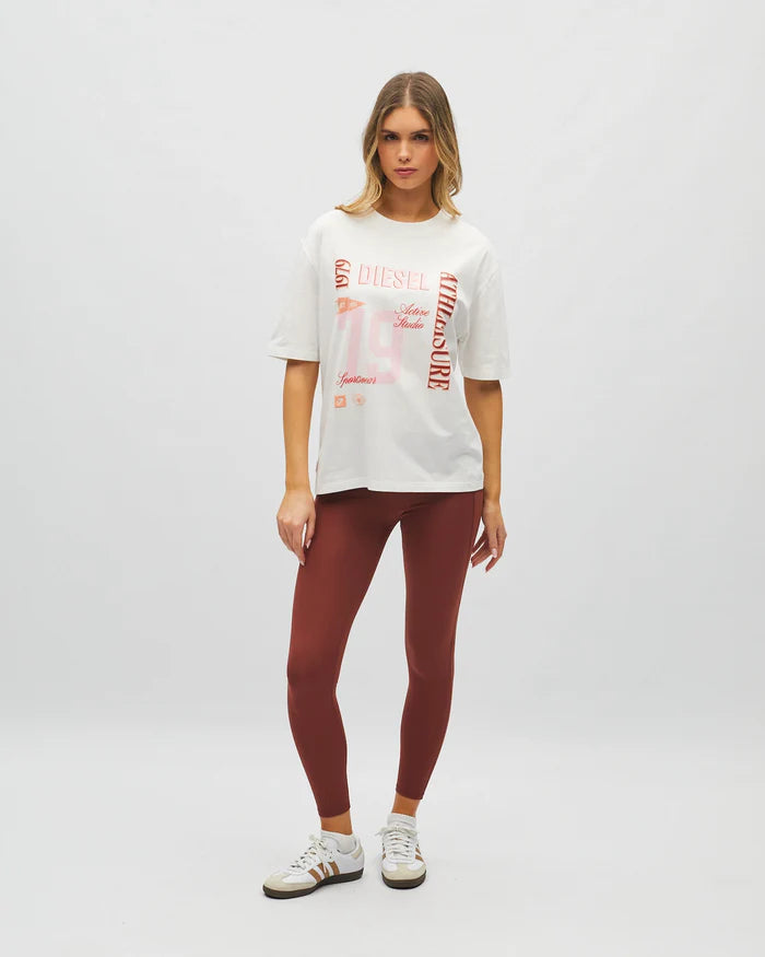 Woman wearing a white graphic t-shirt and maroon leggings on a light gray background