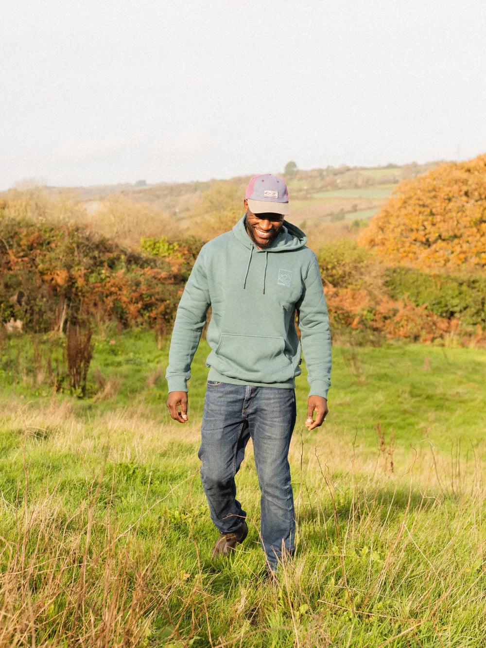 Man walking in a field with trees and grass in the background