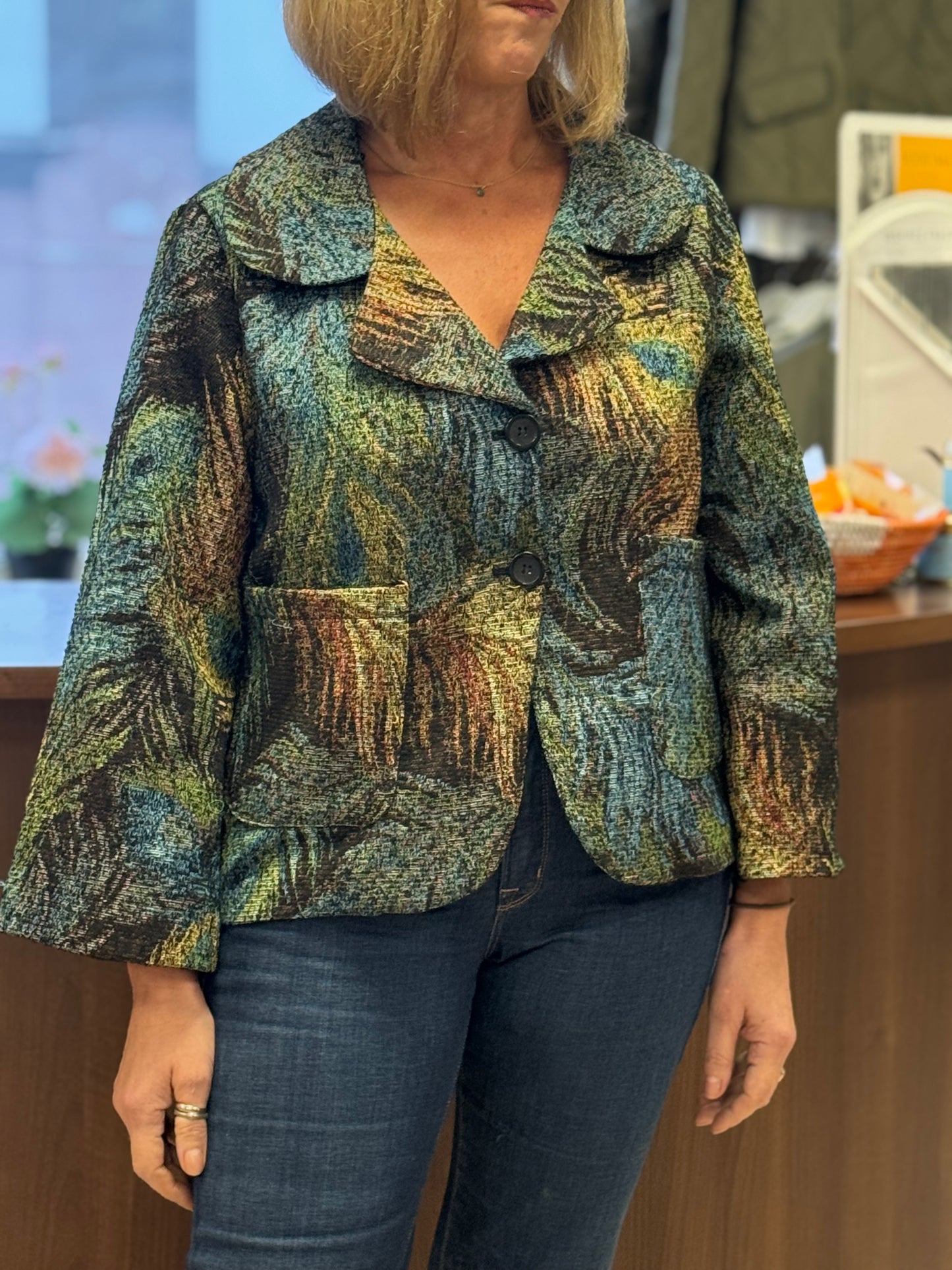 Person wearing a patterned jacket and jeans in an indoor setting
