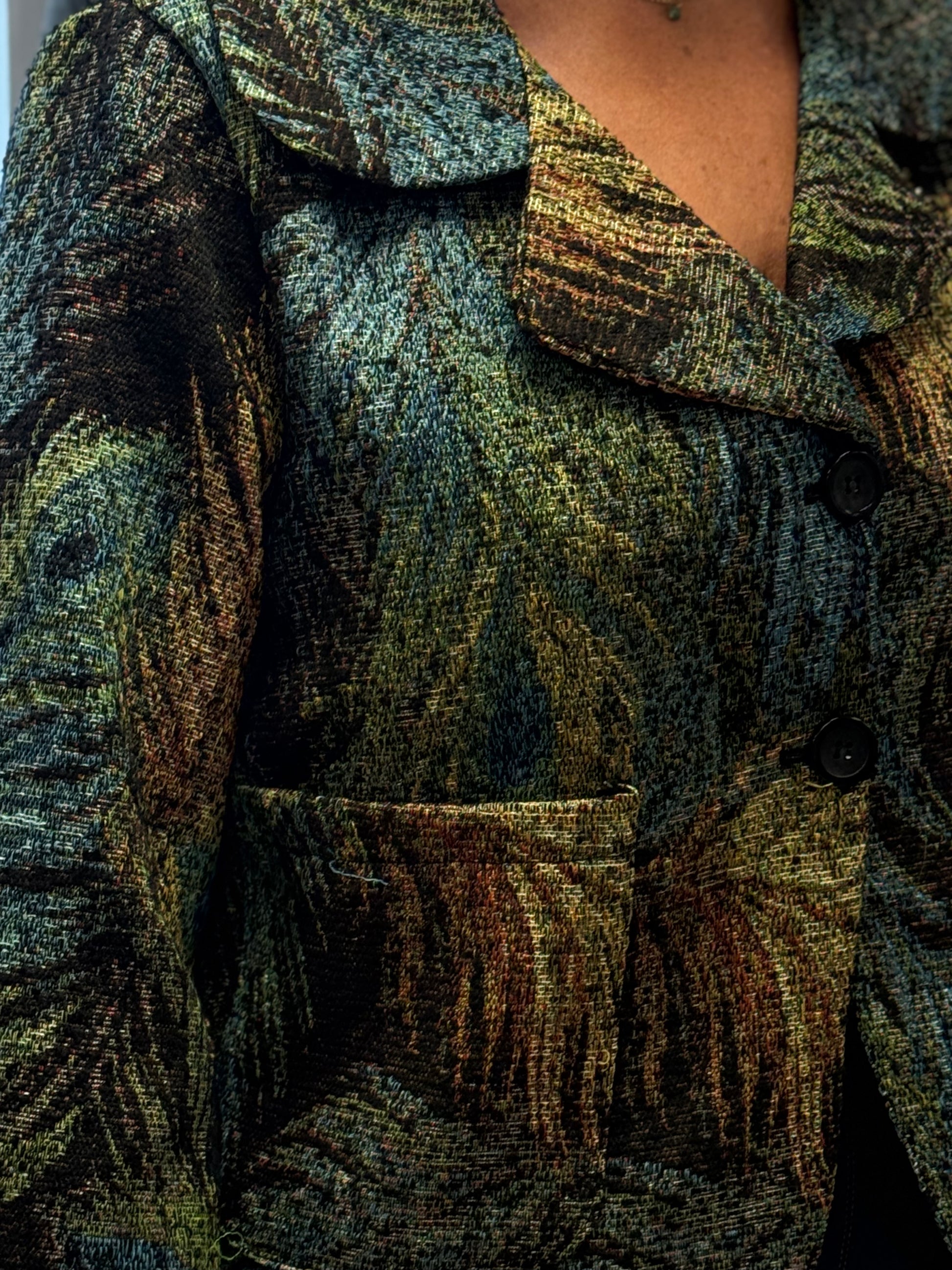 Close-up of a textured green and brown coat with a focus on the fabric and pattern.