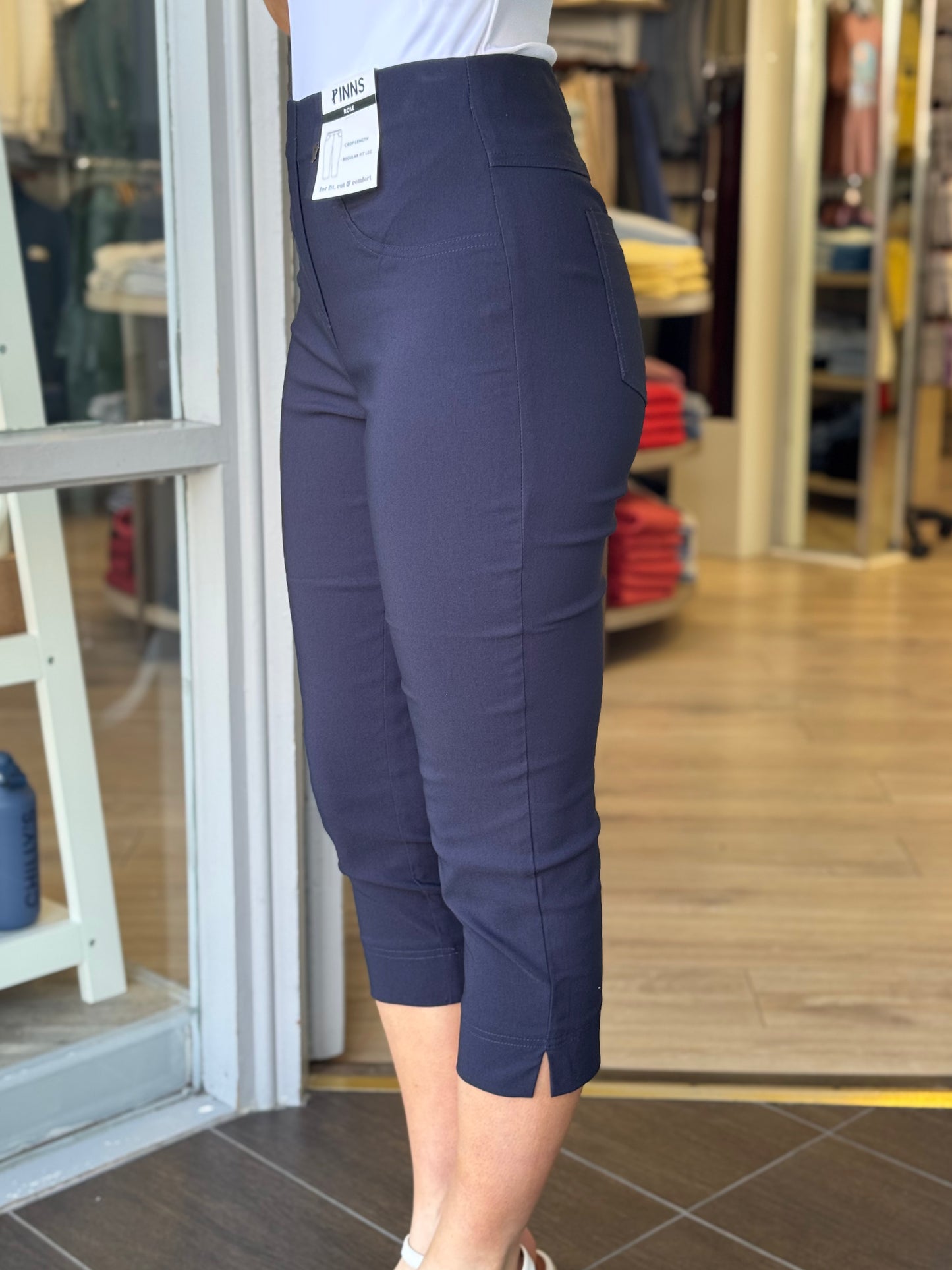 Person wearing navy blue capri pants in a store setting