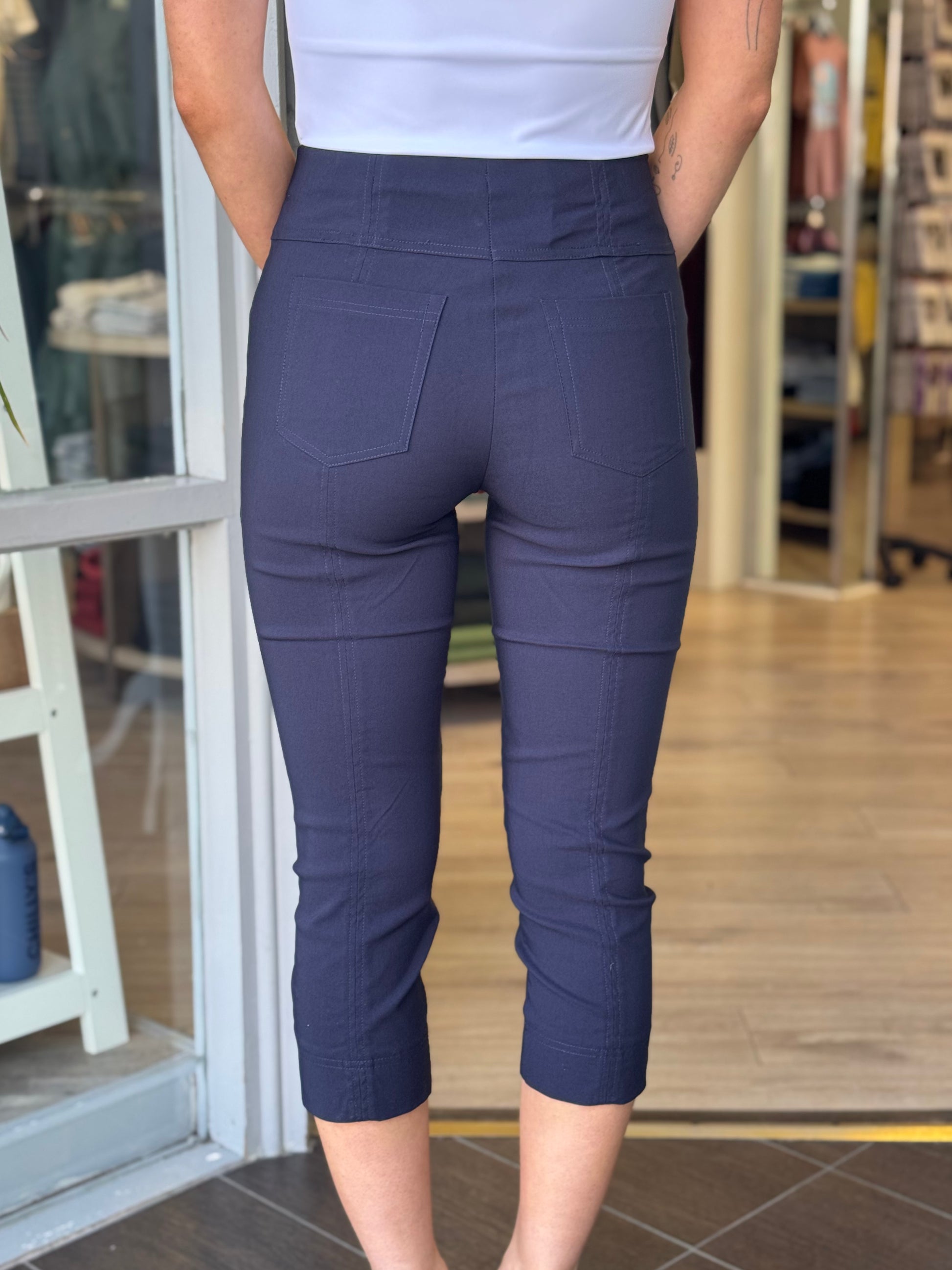 Person wearing navy capri pants in a store setting