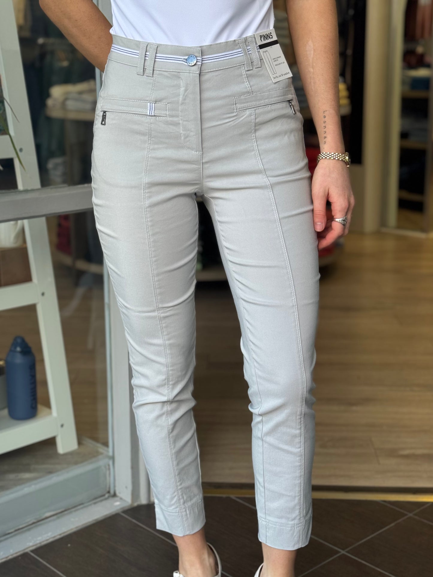 Person wearing light gray pants standing indoors with a blurred background